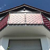 Blick auf einen roten Balkon, die Fassade und die Dachgesimse